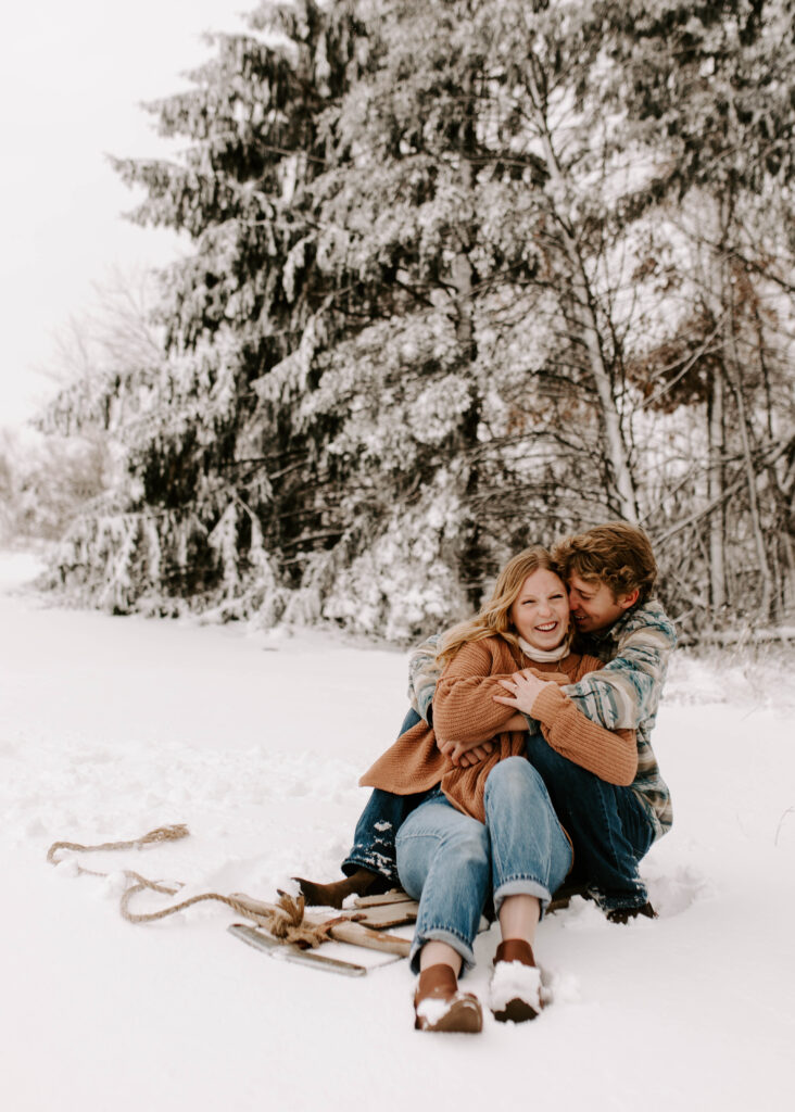 Iowa Wedding Photographer, couple snuggles up on sled after a big snow