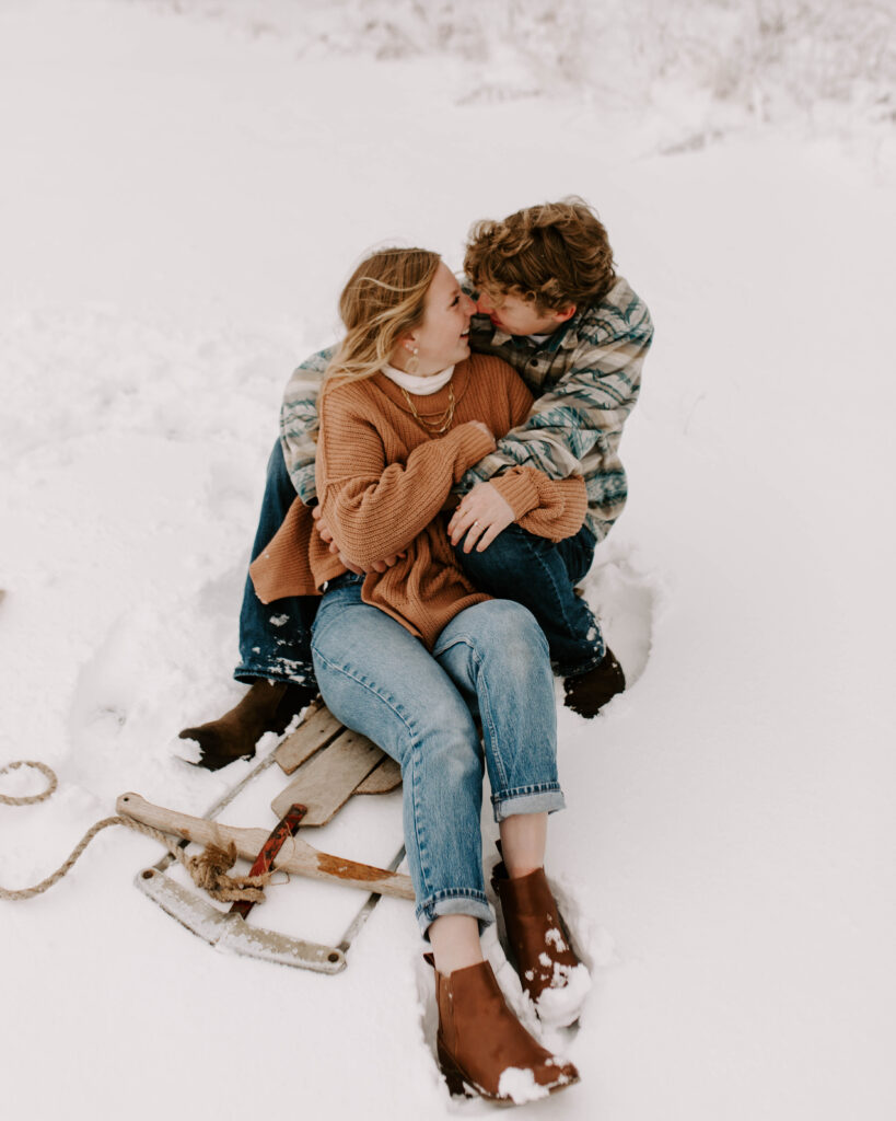 Iowa Wedding Photographer, couple snuggles up on a sled after a big snow