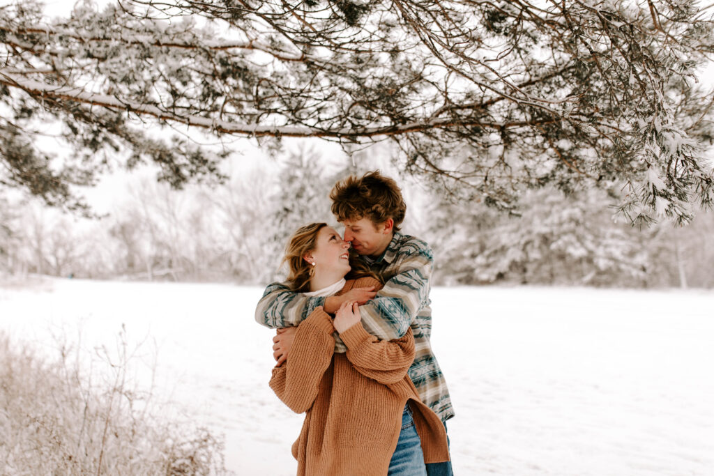 Iowa Wedding Photographer, Couple smiles at each other during their snowy winter engagement session