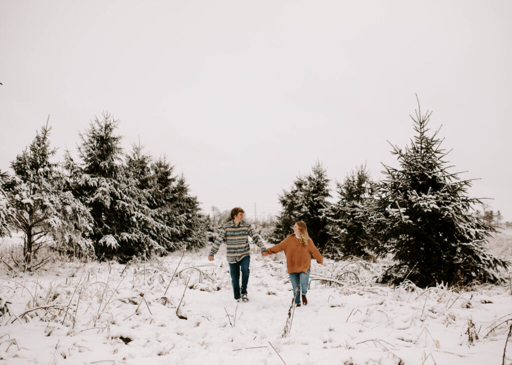 Iowa snowy engagement photos in the winter, couple runs towards the camera in the snow