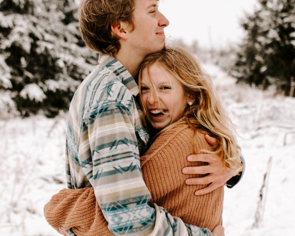 Iowa Wedding Photographer, Couple hugs and smiles in the snow during their winter engagement session
