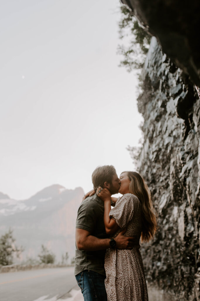 Glacier National Park Weeping Wall, Couple kisses in the rain during adventure engagement session