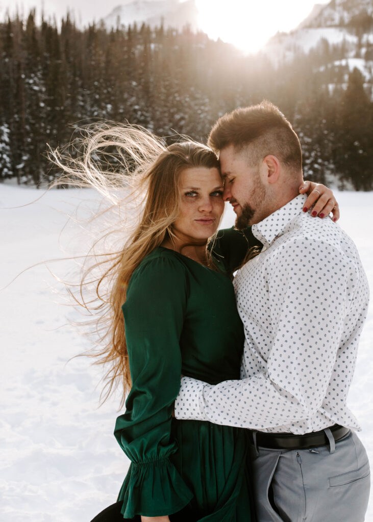 couple stands on frozen lake, she looks at camera