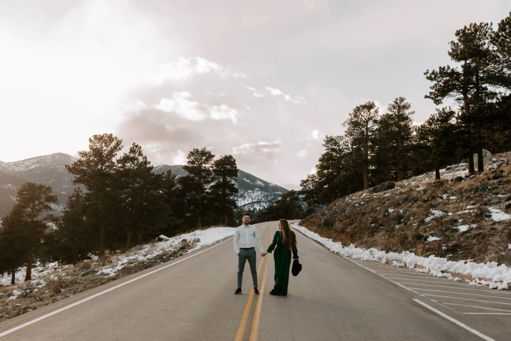 couple stands in road in Rocky Mountain national park 