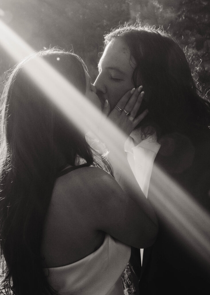 bride and groom kiss in golden light, black and white
