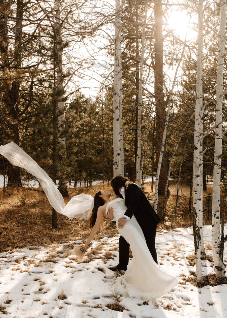 bride and groom dip in the snow during bridal portraits