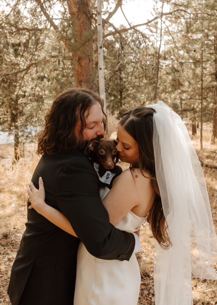 bride and groom snuggle with their dog on wedding day in Colorado 