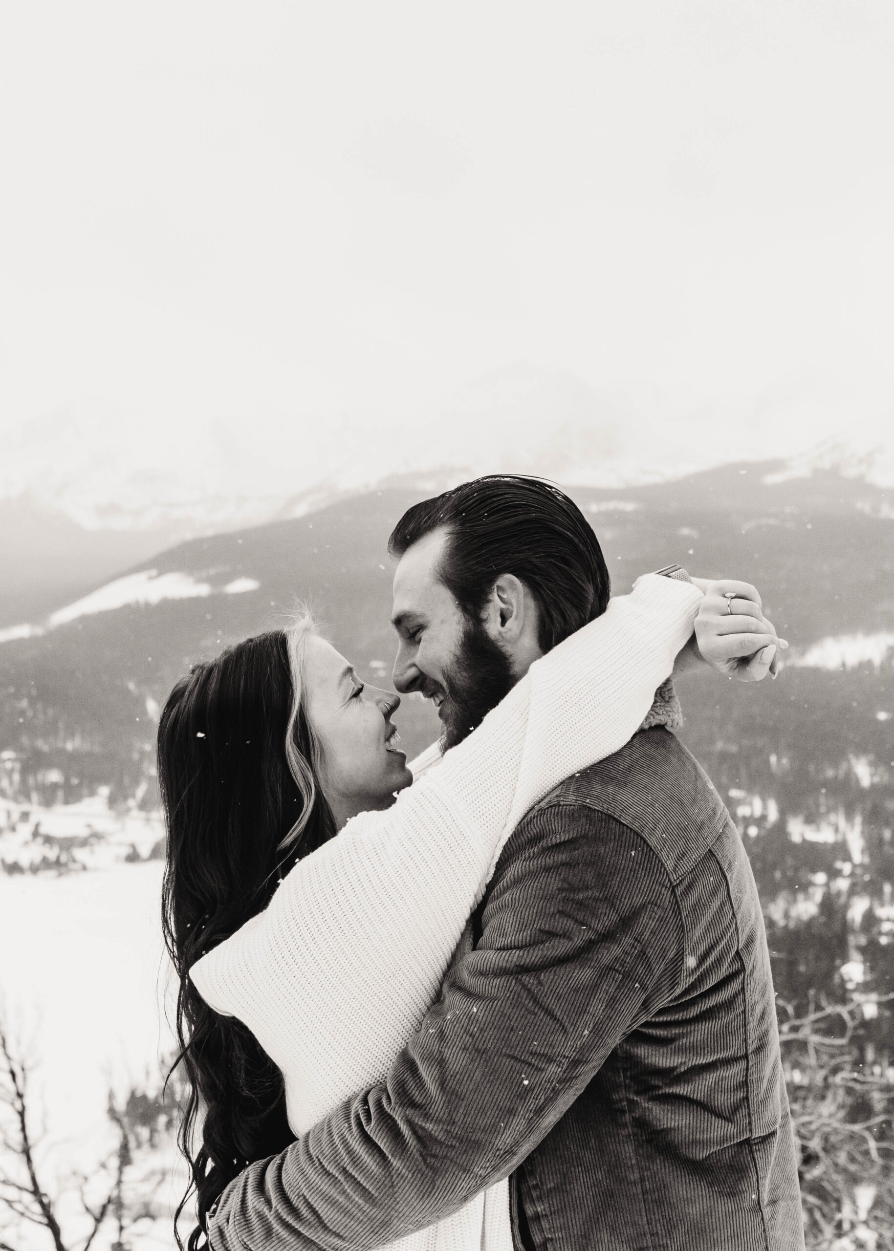couple looks at each other with the look of love in a black and white photo with the mountains in the background