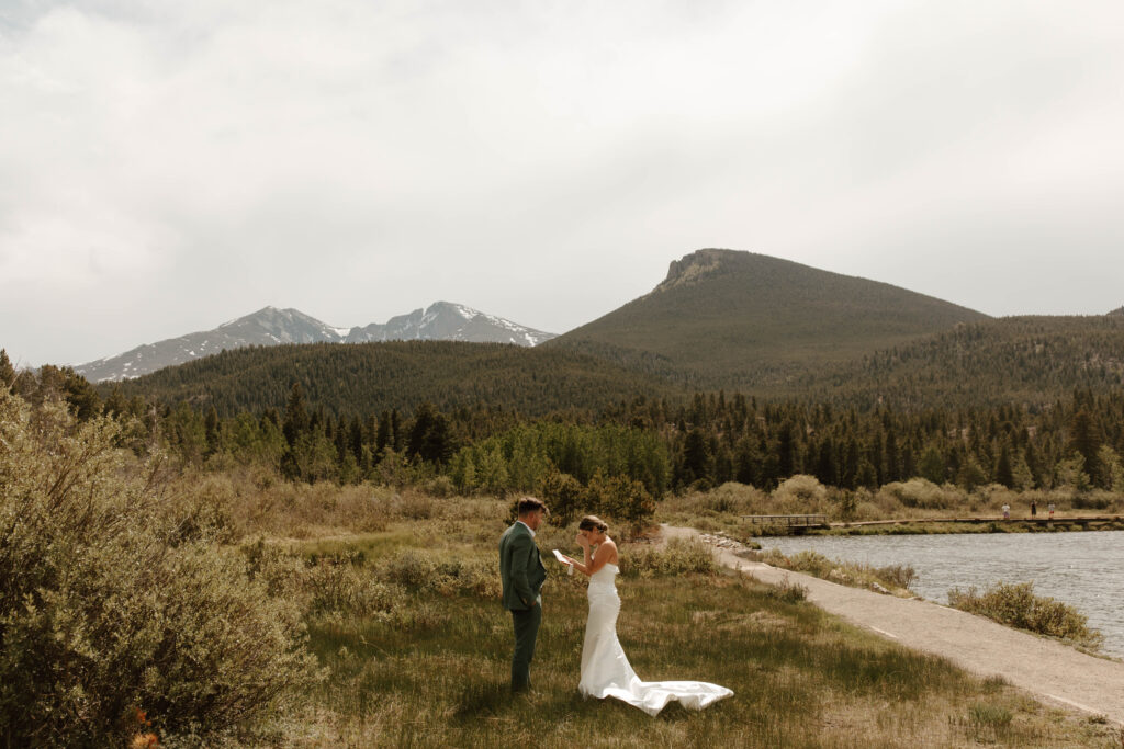 bride and groom exchange vows at lily lake, with a mountain inn the background