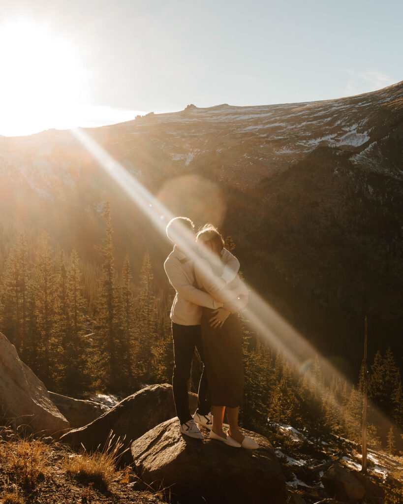 light streams over couple on top of mountain