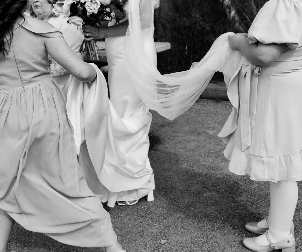 little girls hold brides dress off the ground