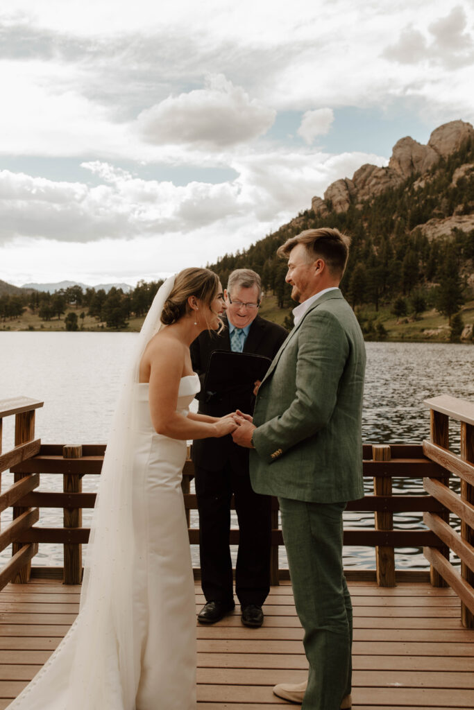 bride and groom laugh on dock of alpine lake