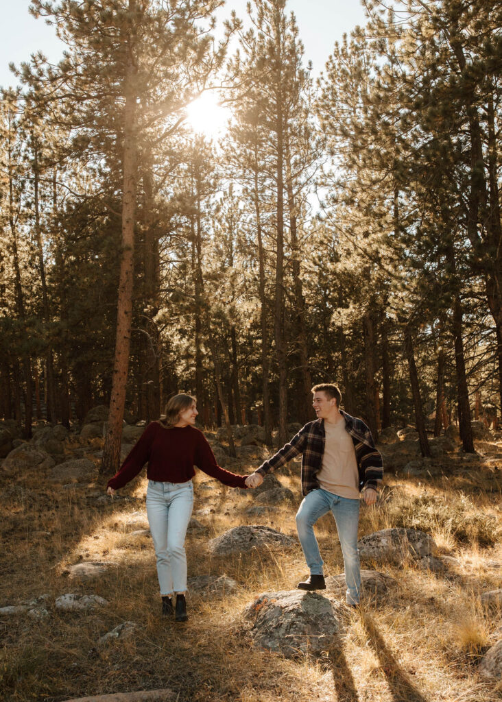 couple holds hands and walks through the woods