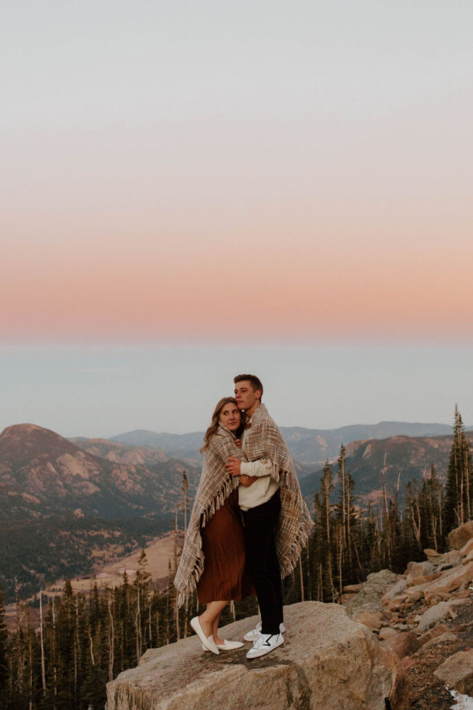 couple looks off into distance with pink skies above them