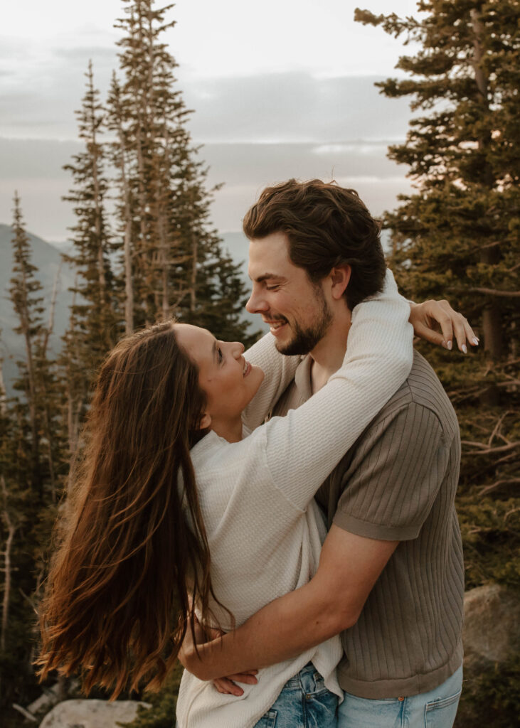 couple embraces and dances together. the Colorado mountains and evergreen trees are behind them