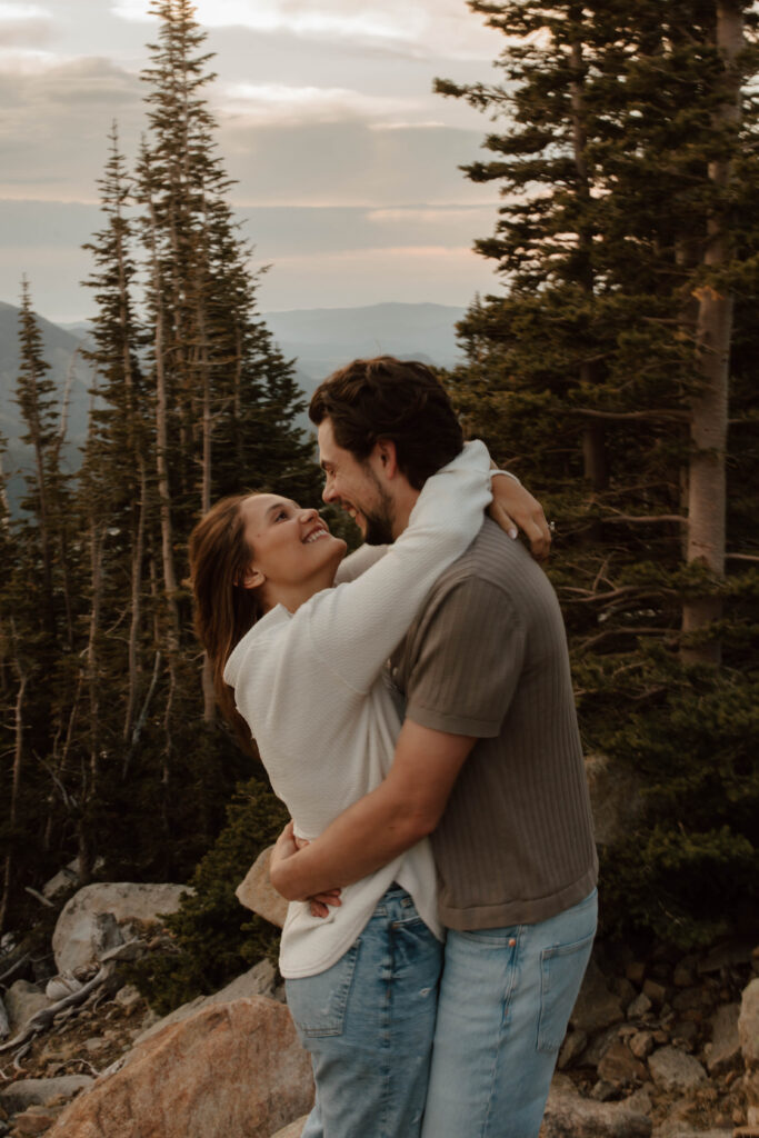 couple embraces and dances together. the Colorado mountains and evergreen trees are behind them