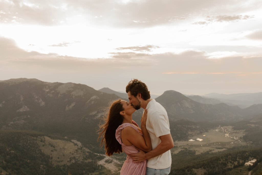 couple kisses during engagement photos on top of Rocky Mountain national park