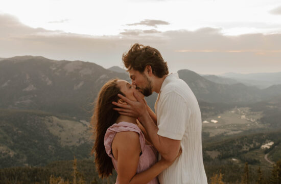 couple kisses on top of mountain