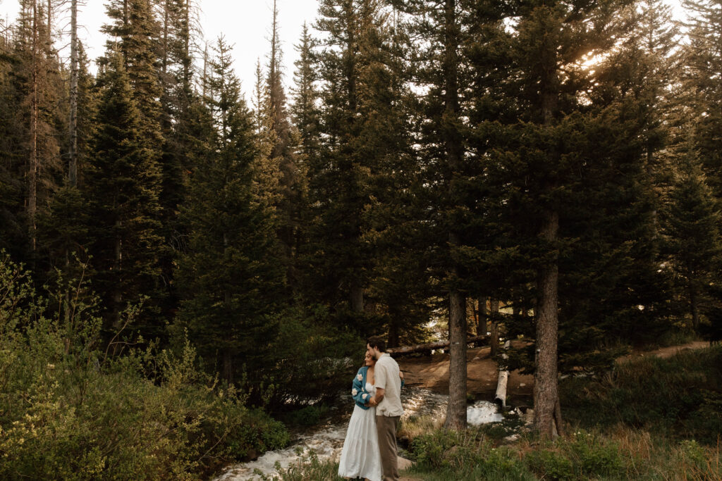 couple hugs next to mountain stream