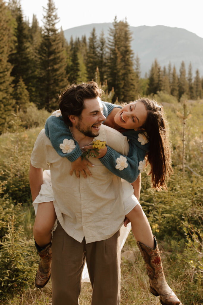 couple piggy back rides in mountain meadow