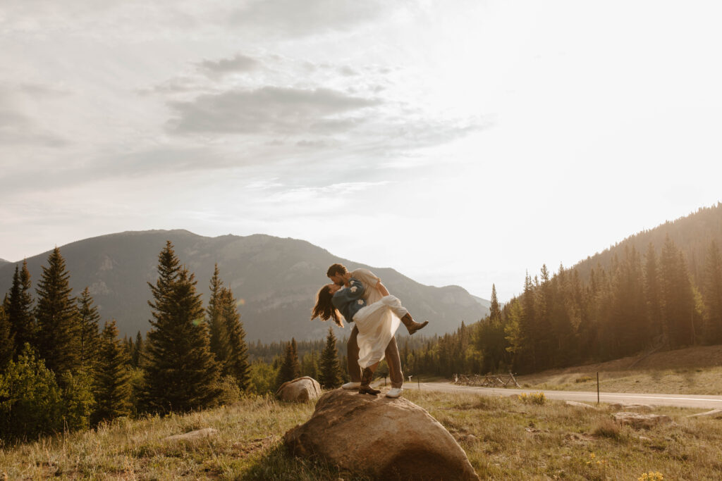 couple dips and kisses on rock in Estes park
