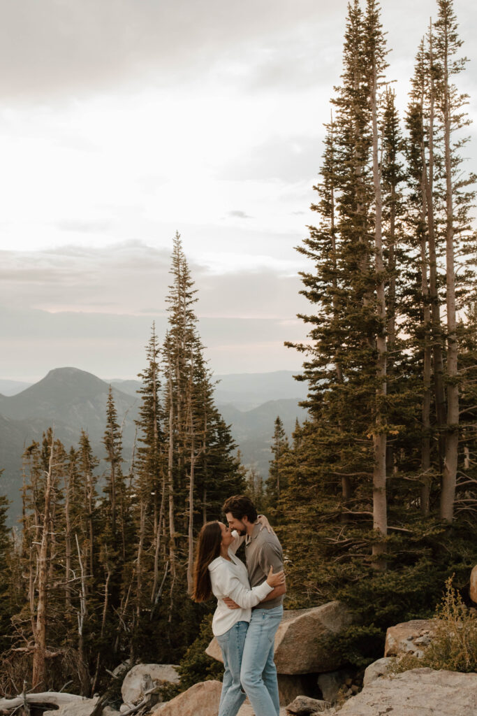 couple embraces and dances together. the Colorado mountains and evergreen trees are behind them