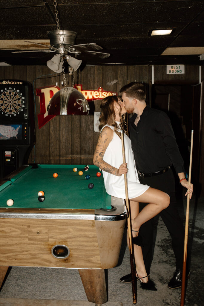 couple leans against pool table and kisses