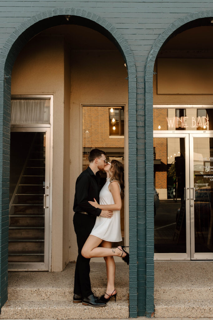 bride and groom kiss leaning against building downtown