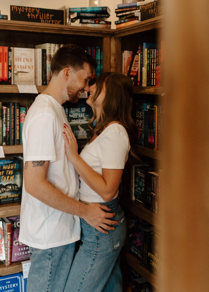 couple snuggles together between book shelves