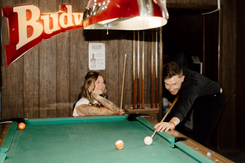 couple smiles while playing pool together