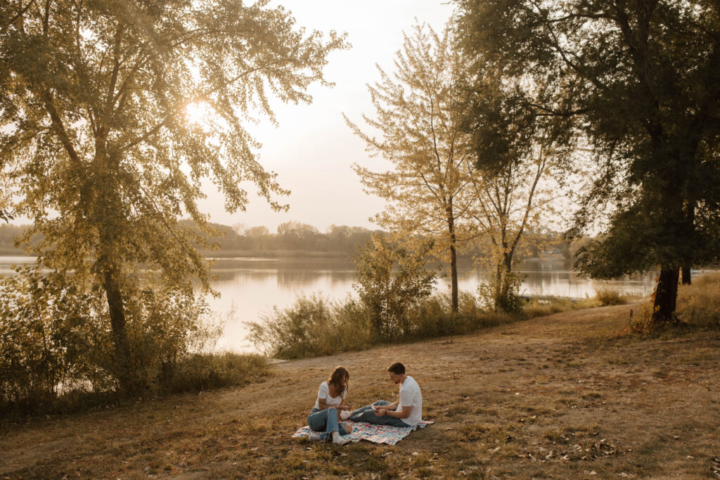 couple plays cards on a picnic blanket during golden hour