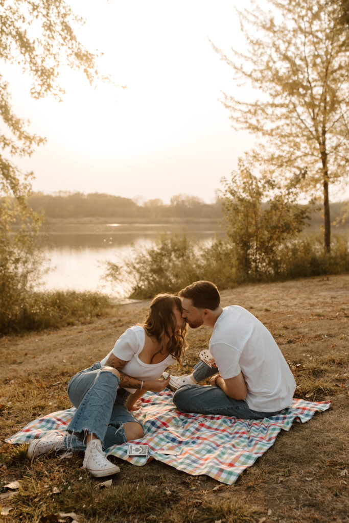 couple kisses on picnic blanket during unique engagement photos