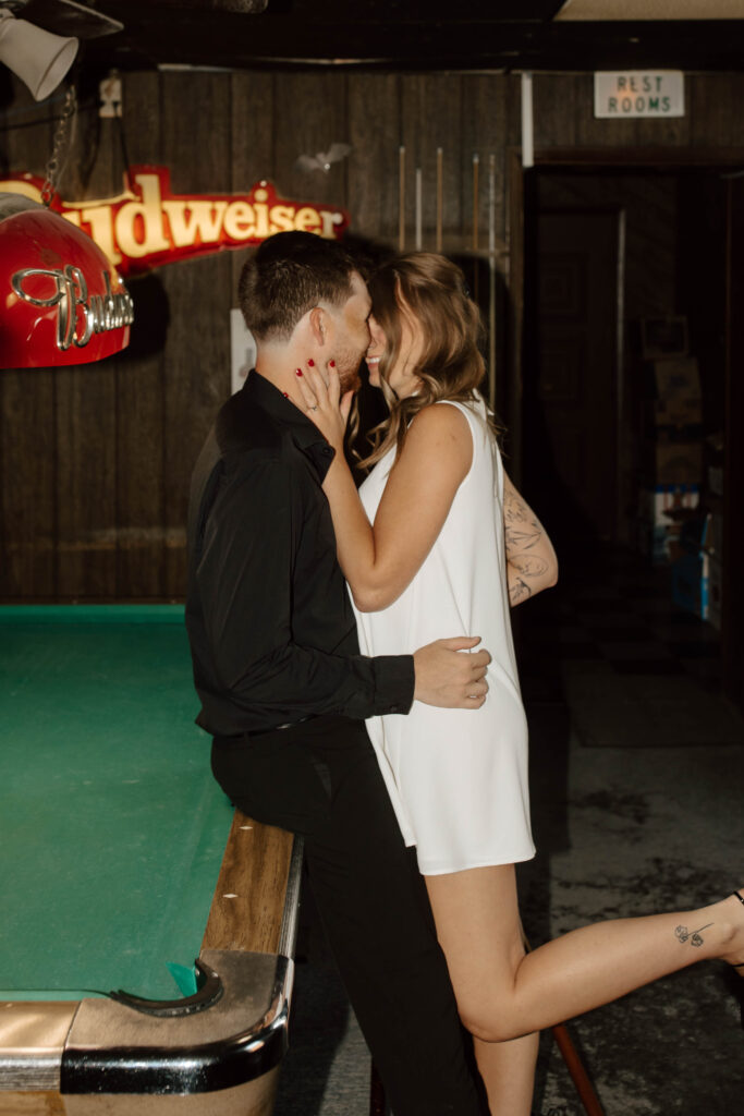 couple kisses at pool table