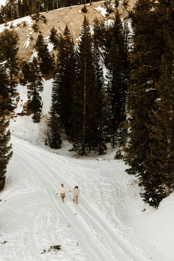 unique creative engagement photos, running in the snow together in the mountains