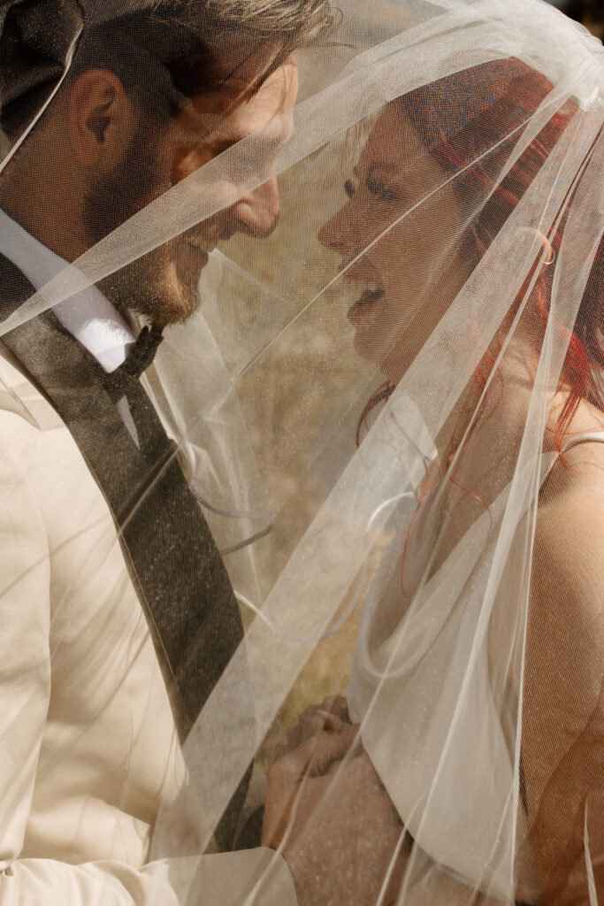 under the veil wedding portraits, laughing together in a candid moment