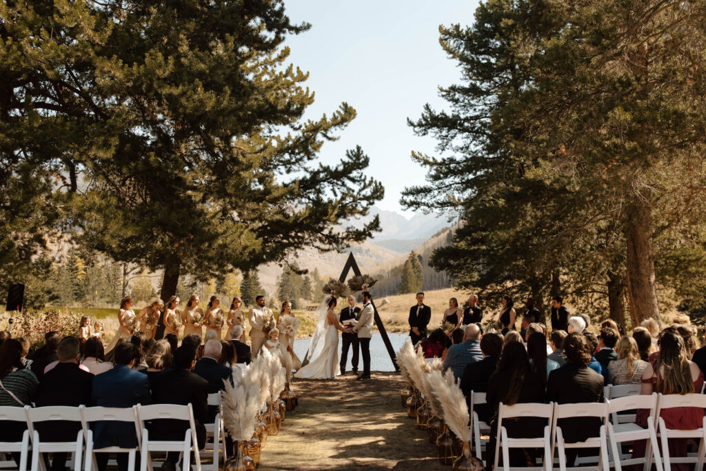 bride and groom stand at vail wedding island in colorado on a pond