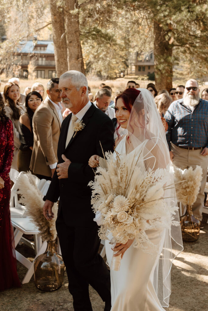 boho colorado bride walks down aisle with her father in summit county colorado wedding